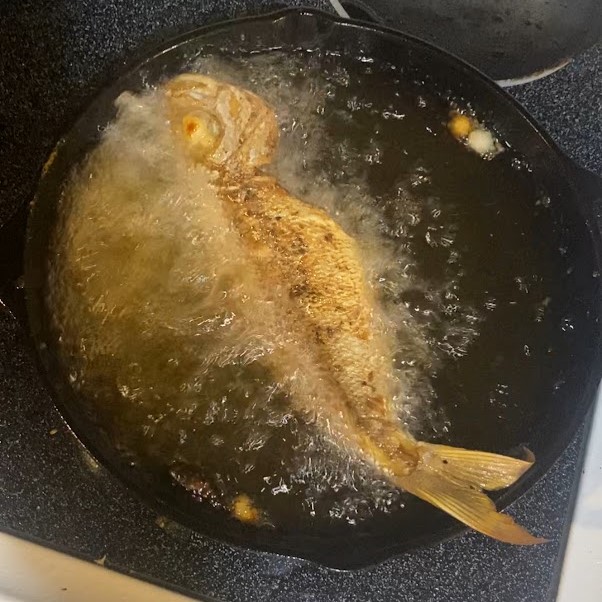 a whole fish frying in a pan