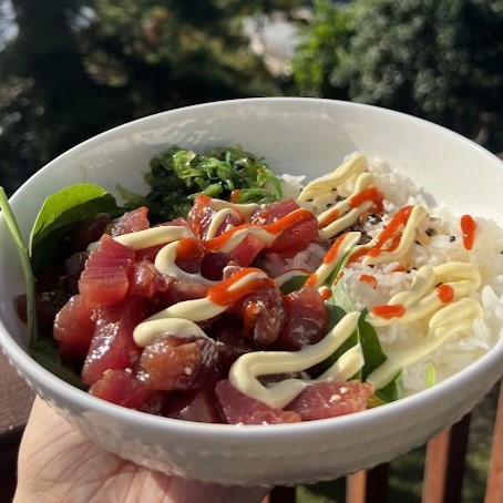 poke bowl with rice, spinach, and mayo and sriracha drizzled on top